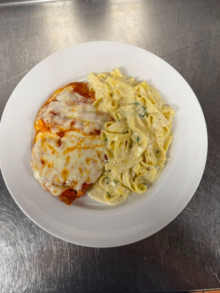 Chicken Parmigiana with Fettuccine Alfredo served on kitchen prep table